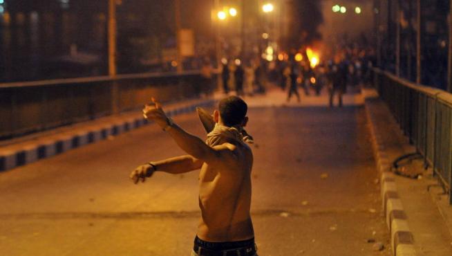 .- Un joven egipcio enfrenta a fuerzas de seguridad egipcias durante una protesta llevada a cabo frente al edificio de la radiotelevisión en El Cairo
