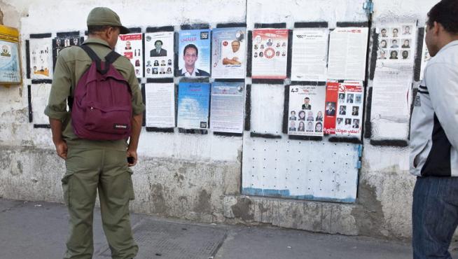 Un soldado tunecino observa varios carteles electorales