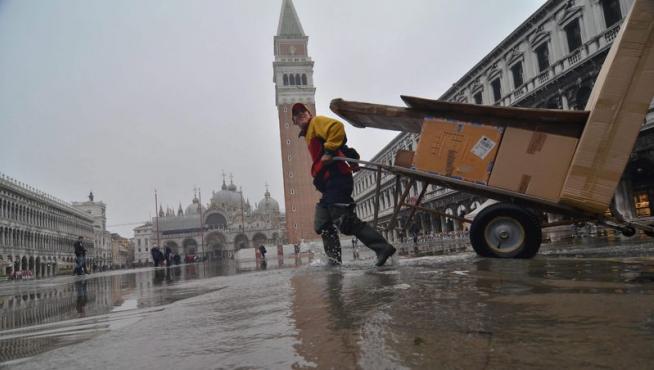 Un hombre empuja sus pertenencias por las calles inundadas de Venecia