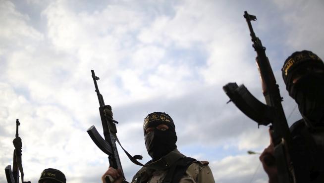 Varios militantes de la yihad islámica alzan sus armas durante un funeral