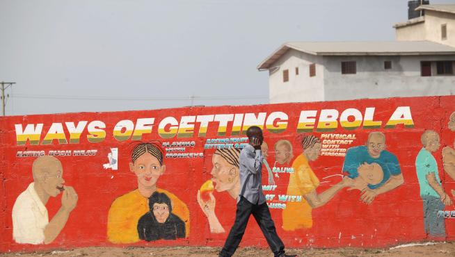 Un ciudadano de Liberia pasea por delante de un mural divulgativo pintado para concienciar sobre la epidemia de ébola.