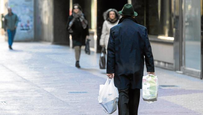 Un transeúnte pasea por Zaragoza con dos bolsas de plástico.