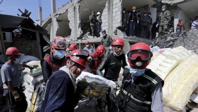 Miembros de los equipos de rescate trasladan a una víctima rescatada entre los escombros en Pedernales, Ecuador.