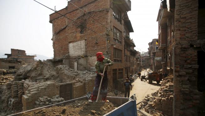 Una mujere trabaja en la reconstrucción de una vivienda en Nepal, un año después del terremoto.