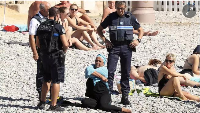 La policía obliga a una mujer a quitarse el burkini en una playa de Niza.