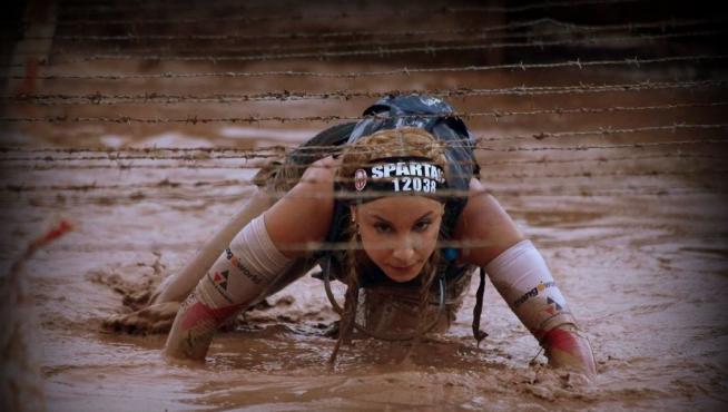 Natalia Castiella reptando bajo un alambre de espino en una Spartan race.
