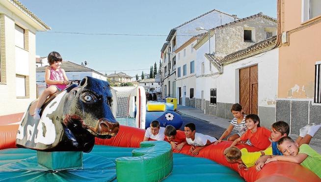 Varios niños disfrutan de los hinchables y el toro mecánico instalados en una de las calles del municipio oscense.
