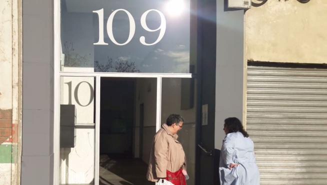 Dos vecinas observan la puerta robada en el número 109 de la calle Miguel Servet, en Zaragoza.