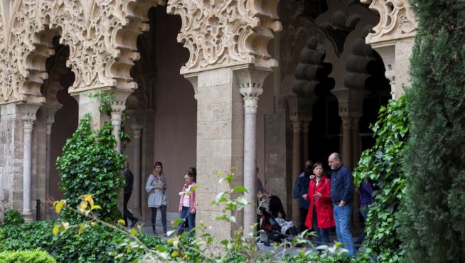Visitantes bajo los arcos de patio central del palacio de la Aljafería, en Zaragoza.