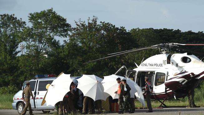 Miembros del ejército y de la policía cubren con paraguas el helicóptero en el que son evacuados los niños