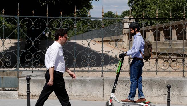 Un hombre conduce en París un patinete eléctrico de la marca Lime