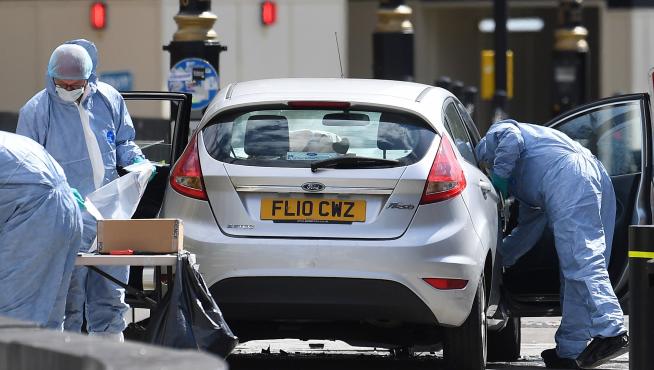 Oficiales forenses examinan el coche que chocó contra las barreras del Parlamento británico en Londres.