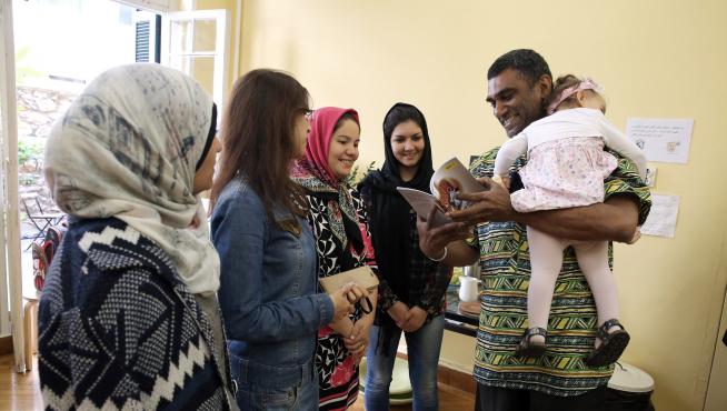 El secretario general de AI sostiene en sus brazos a una bebé inmigrante en un centro de mujeres de Atenas.