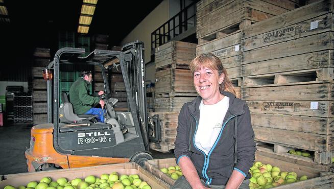 La agricultora Fina Martínez sonríe junto a las manzanas recolectadas