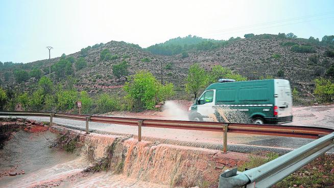 Una torrentera anega y cruza la carretera N-330, también cortada por la caída de rocas, entre Teruel y Villastar.