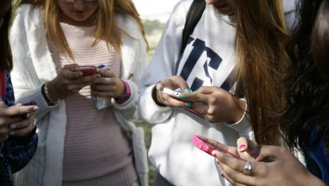 Varios jóvenes usando móviles.