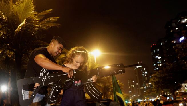 Un hombre a favor del acceso a las armas en Brasil posa junto a una niña en una manifestación en Río