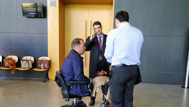 El demantante, en silla de ruedas, junto a su abogado, Víctor Laguardia, hablando por teléfono.