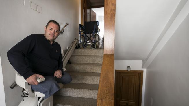 Eugenio Rodríguez, en la silla elevadora instalada en las escaleras que dan acceso a su vivienda en Zaragoza.