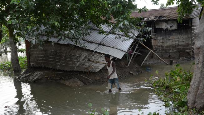 Un hombre camina cerca de su casa, afectada por las inundaciones, en la región de Assam (India).