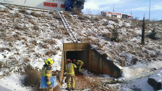 Los bomberos de la DPT actuando para evitar un vertido de gasóleo tras el accidente de un camión en la Vía Perimetral de Teruel a causa de la nieve.