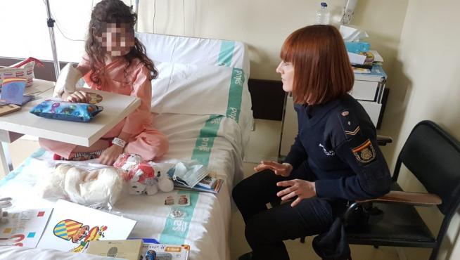 Una policía nacional charla con una niña hospitalizada