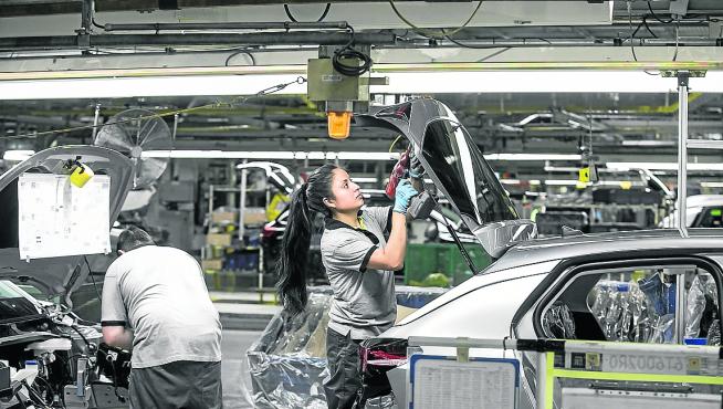 Operarios trabajan en una cadena de montaje de la factoría zaragozana de Opel PSA.