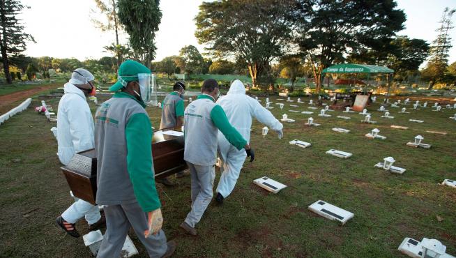 Trabajadores del cementerio Campo de Esperanza entierran una víctima de la pandemia este jueves, en Brasilia (Brasil).
