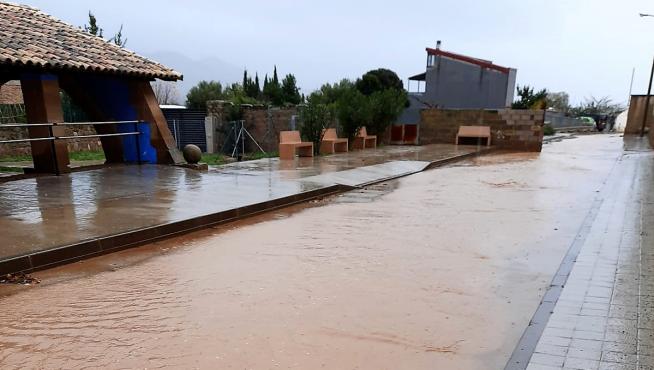 Agua acumulada en una calle de Apiés tras la lluvia de este sábado.