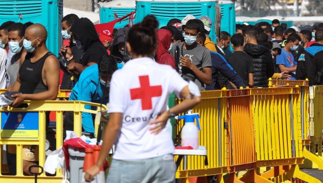 Una voluntaria de Cruz Roja mira a los inmigrantes en el puerto de Arguineguín