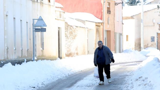 Un vecino camina por una calle de Bello cubierta de hielo.