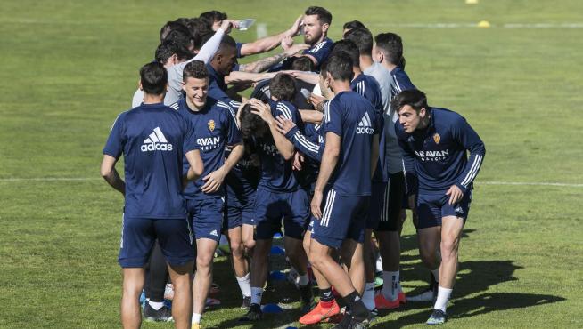 Los jugadores del Real Zaragoza, en una piña de castigo para los perdedores en un ejercicio táctico, dentro del buen ambiente que reina en el grupo.
