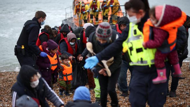 Migrants are brought ashore by RNLI Lifeboat staff, police officers and Border Force staff, after having crossed the channel, in Dungeness