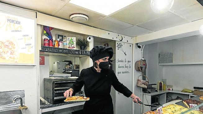 Soraya Ferrer prepara porciones de pizza en su establecimiento.