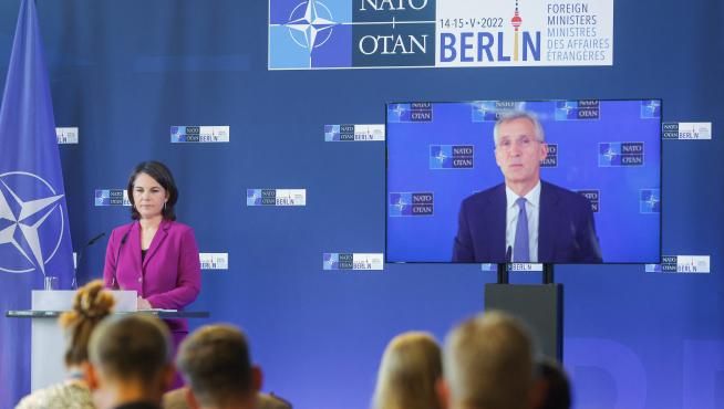 La ministra alemana de Exteriores, Annalena Baerbock, y en pantalla, el secretario general de la OTAN, Jens Stoltenberg.