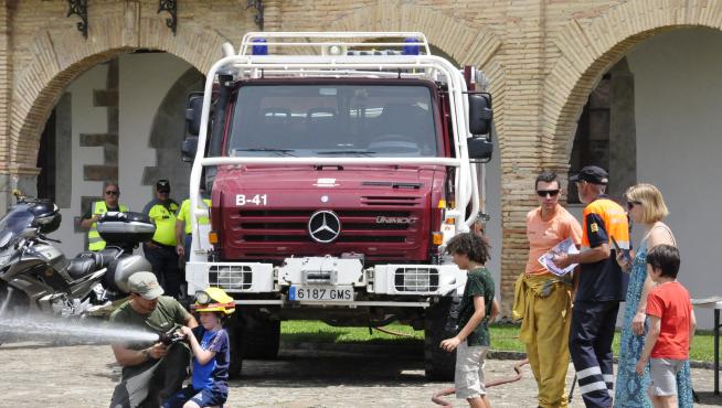Un bombero enseña a un niño a usar una manguera.