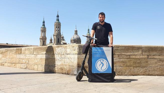 Carlos Sánchez, el fisio sobre ruedas, con su patinete y camilla, en el puente de Piedra de Zaragoza, este viernes.