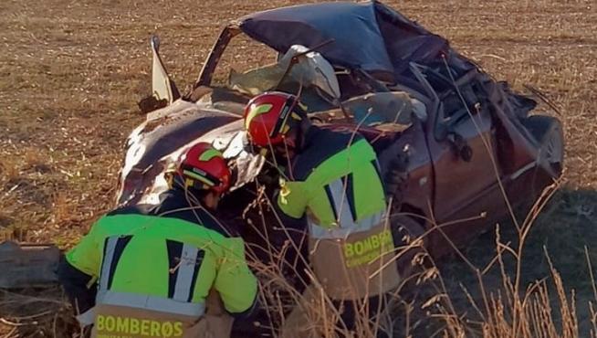 Los bomberos de la DPT inspeccionan el coche siniestrado en Alcorisa.