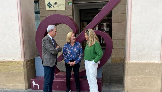 Salvador Cored, Rosa Gerbás y Susana Lacostena junto al logo del comercio de Huesca colocado delante de la sede de CEOS-Cepyme