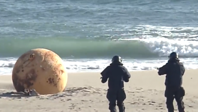 Dos artificieros se acercan a la esfera en la playa