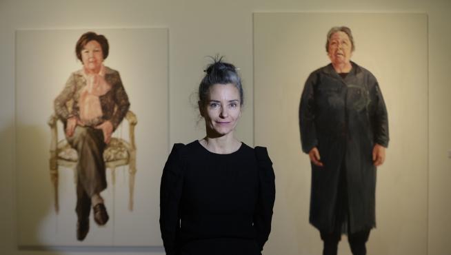 La pintora María Buil, este miércoles 1 de marzo, flanqueada por dos de sus obras en el Paraninfo.