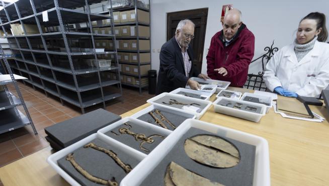 Los arqueólogos Francisco Burillo –izda.– y Raúl Ibáñez, con Elena Almazán, trabajadora del Museo de Albarracín, con armas y objetos de la necrópolis de Bronchales.