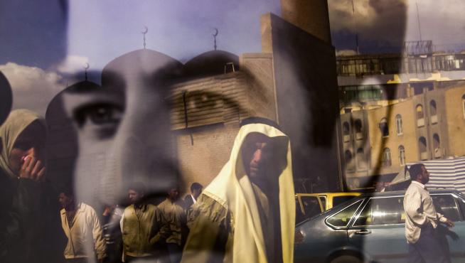 personas que caminan por la calle Rasheed se reflejan en un retrato en blanco y negro del presidente iraquí Saddam Hussein en Bagdad IRAQ PHOTO SET INVASION 20TH ANNIVERSARY