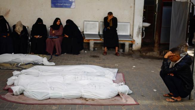 People sit next to the bodies of Palestinians killed in Israeli strikes, amid the ongoing conflict between Israel and the Palestinian Islamist group Hamas, at a hospital in Rafah, in the southern Gaza Strip, December 4, 2023. REUTERS/Mohammed Salem [[[REUTERS VOCENTO]]]