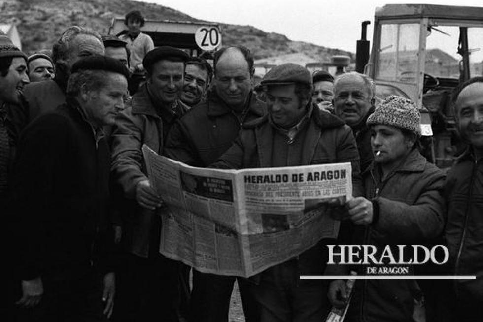 Unos agricultores afectados por la guerra de los precios del maíz leyendo HERALDO DE ARAGÓN para informarse sobre la 'tractorada' que realizaron en enero de 1976 en la provincia de Zaragoza, en un año donde aumentó notablemente el número de huelguistas y paros.