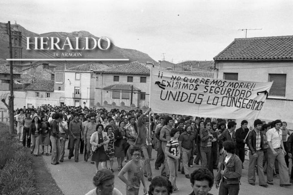 Los vecinos de Utrillas protestan por la falta de seguridad en el trabajo y los deficientes servicios sanitarios tras una semana negra en la Cuenca Minera Turolense con seis muertos por accidente laboral. La imagen corresponde al 13 de junio de 1978 durante el entierro en Utrillas del último fallecido donde los compañeros ondean una pancarta, en silencio, bajo el lema: ¡¡No queremos morir!! Exigimos seguridad. Unidos lo conseguiremos.