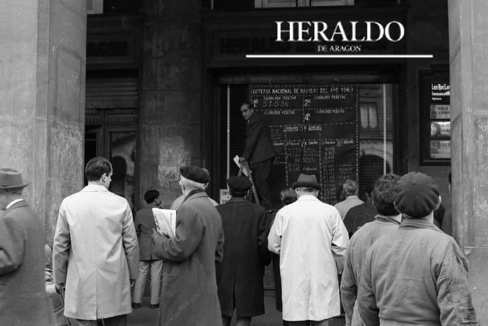 Imagen que se repite año tras año, cada 22 de diciembre, en la puerta de HERALDO DE ARAGÓN, en el paseo de la Independencia 29 de Zaragoza. La gente mira expectante los números premiados del sorteo del Gordo de la Lotería de Navidad. La fotografía corresponde al 22 de diciembre de 1969, año en el que el Gordo correspondió al número 59.536 y Zaragoza se llevó dos premios de un millón de pesetas.
