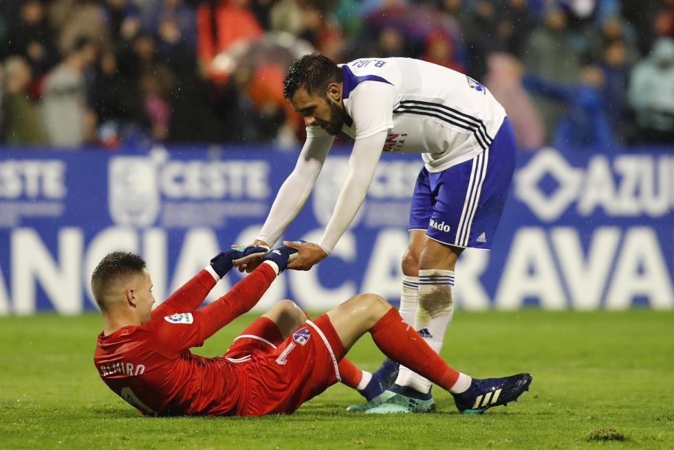 Borja Iglesias, delantero del Real Zaragoza, ayuda a Álex Remiro, portero del Huesca, en el último derbi aragonés.