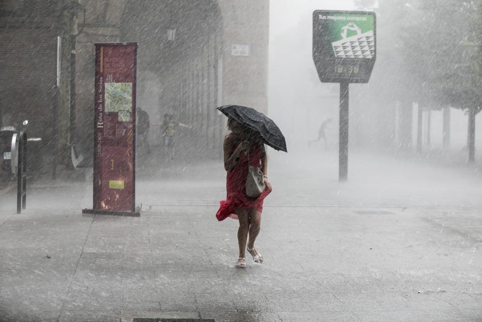 Una mujer trata de resguardarse de la lluvia en el Paseo de la Independencia