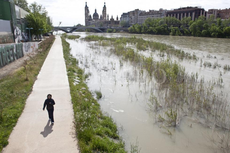 Vista del río Ebro a su máximo nivel entre los puentes de Santiago y La Almozara de Zaragoza. Al fondo, la Basilica del Pilar